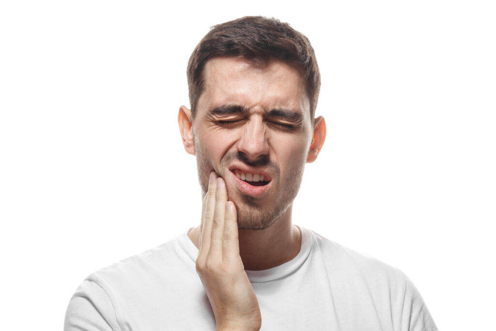 man holding his jaw against a white background, severe tooth pain and possible need for root canal