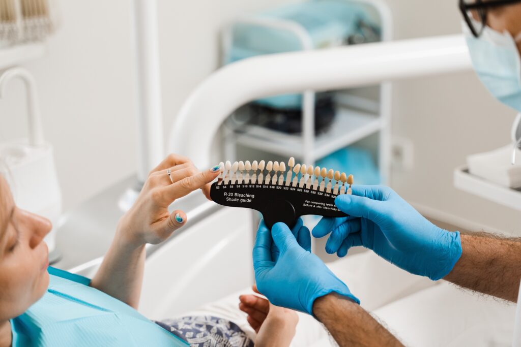 doctor in blue gloves showing a patient her options for porcelain veneers