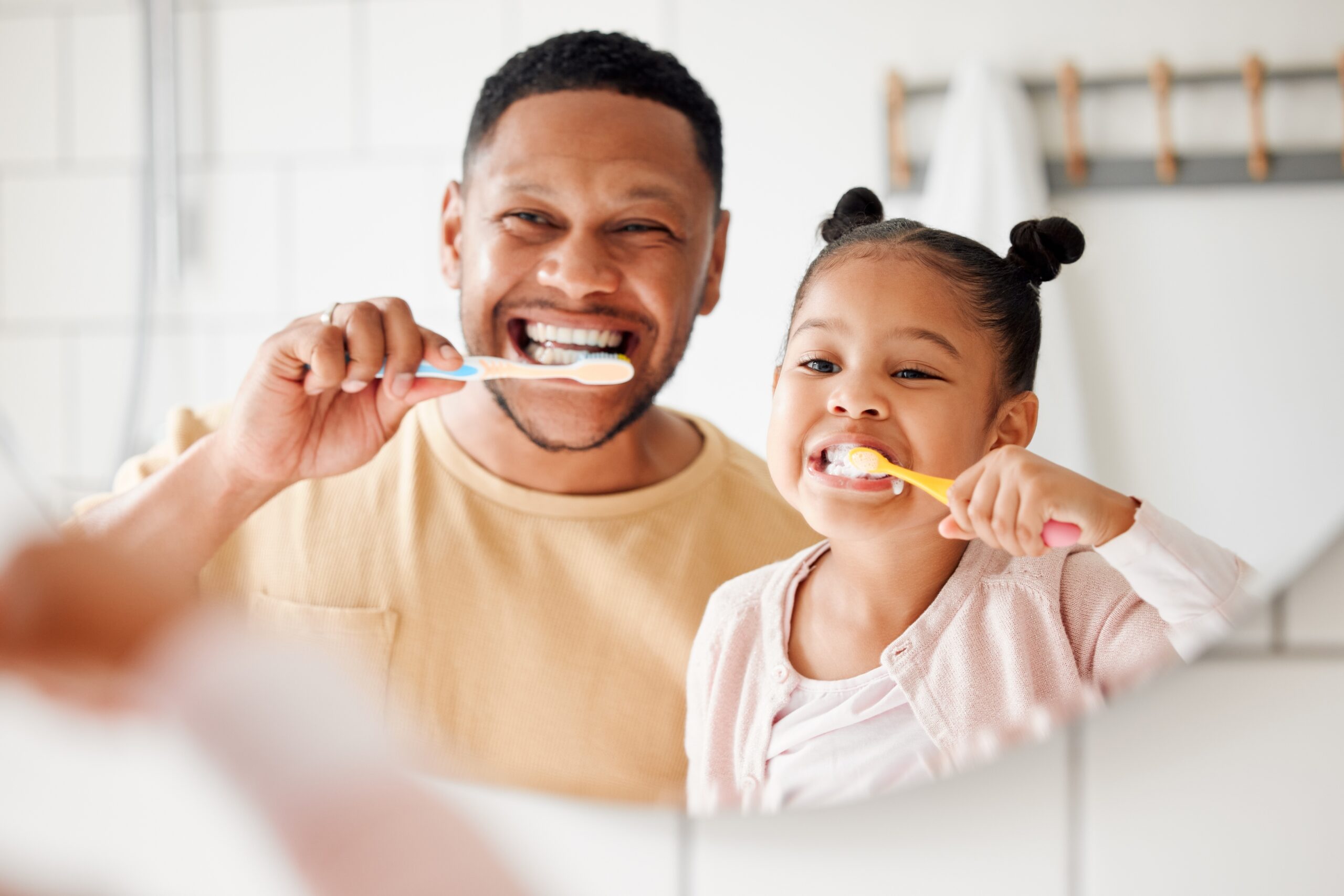 father and daughter brushing teeth in a family home for dental health and wellness in a mirror
