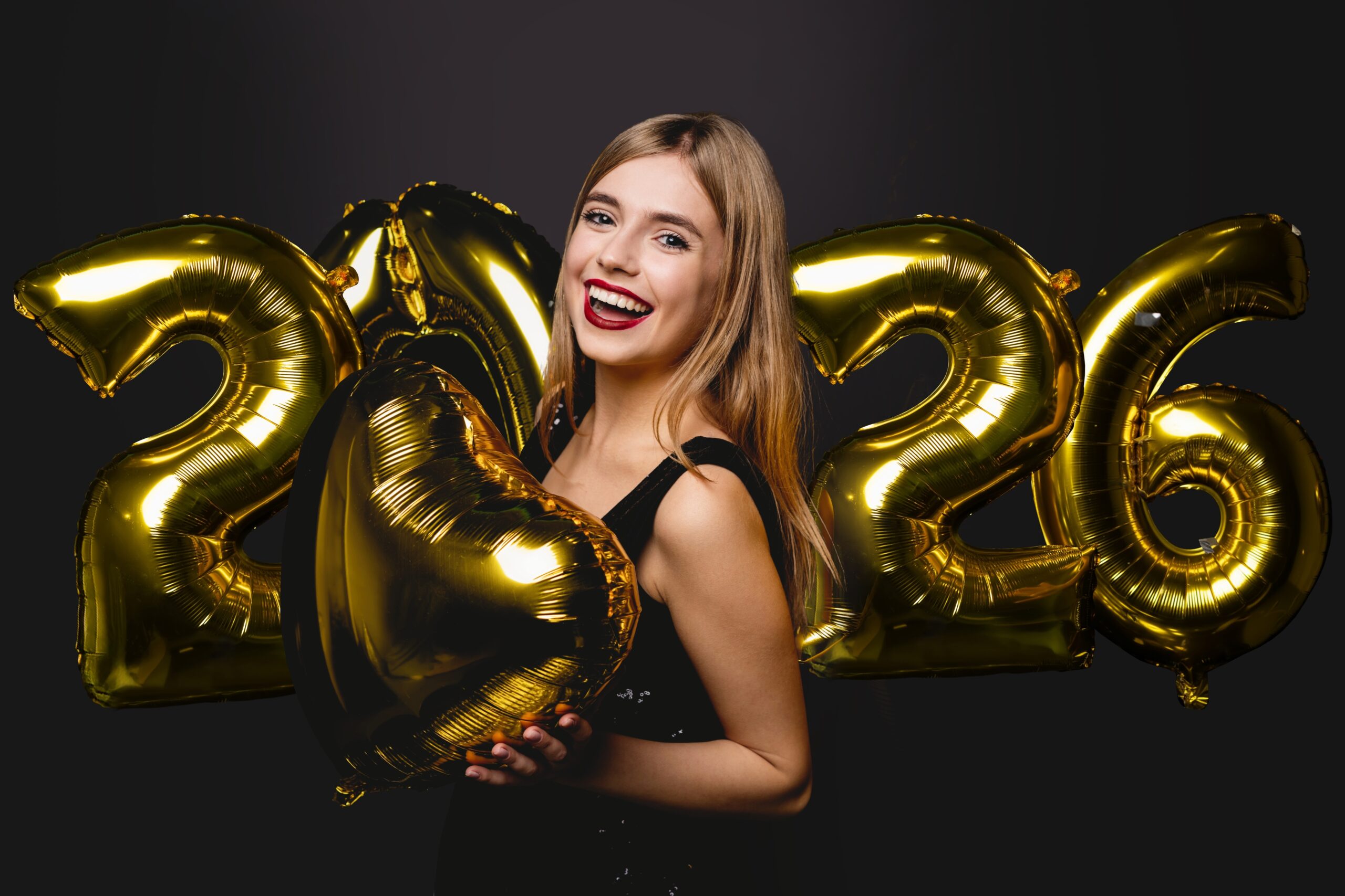young woman holding 2026 balloons smiling, perfect white teeth