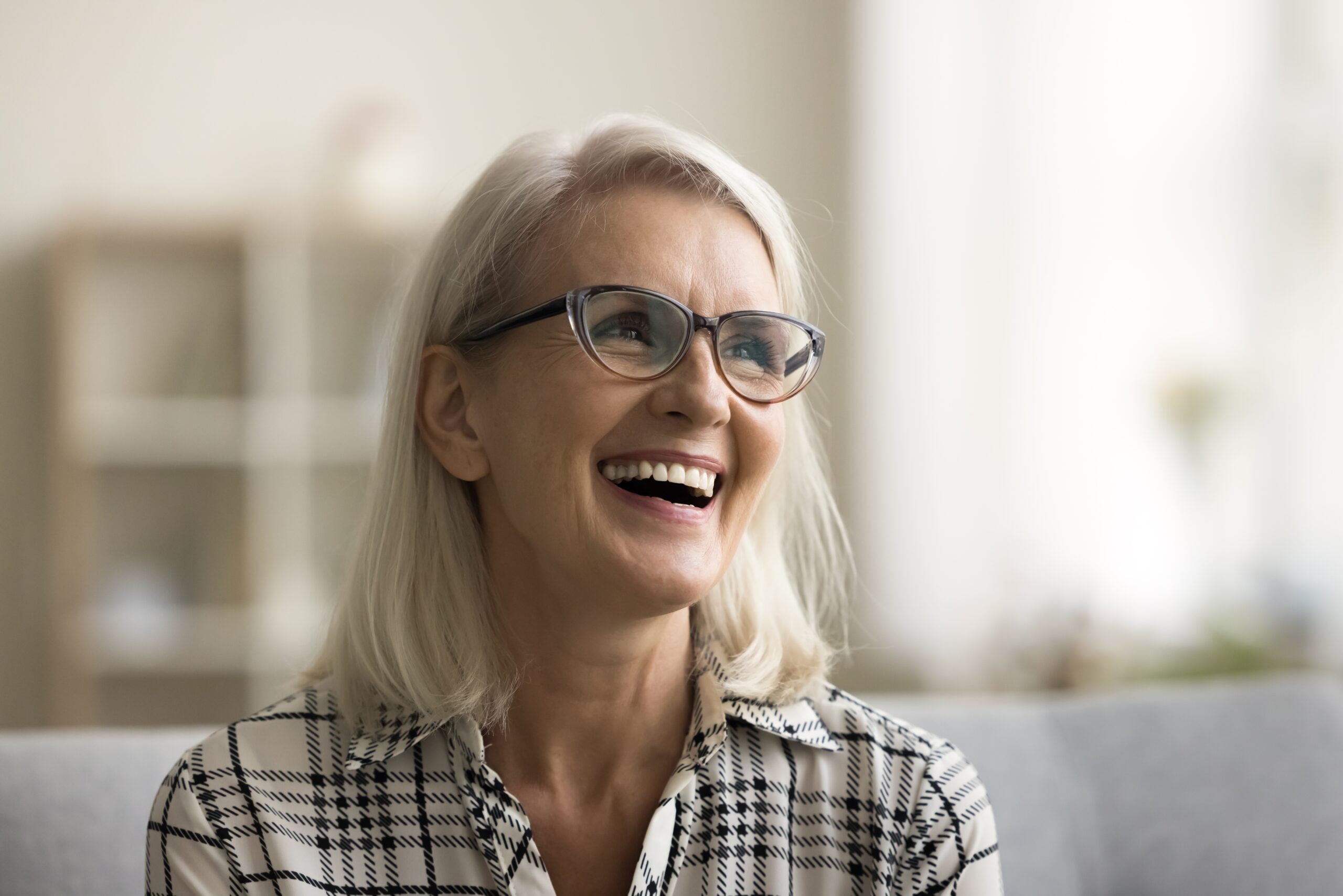 mature woman smiling on a couch, dental implants