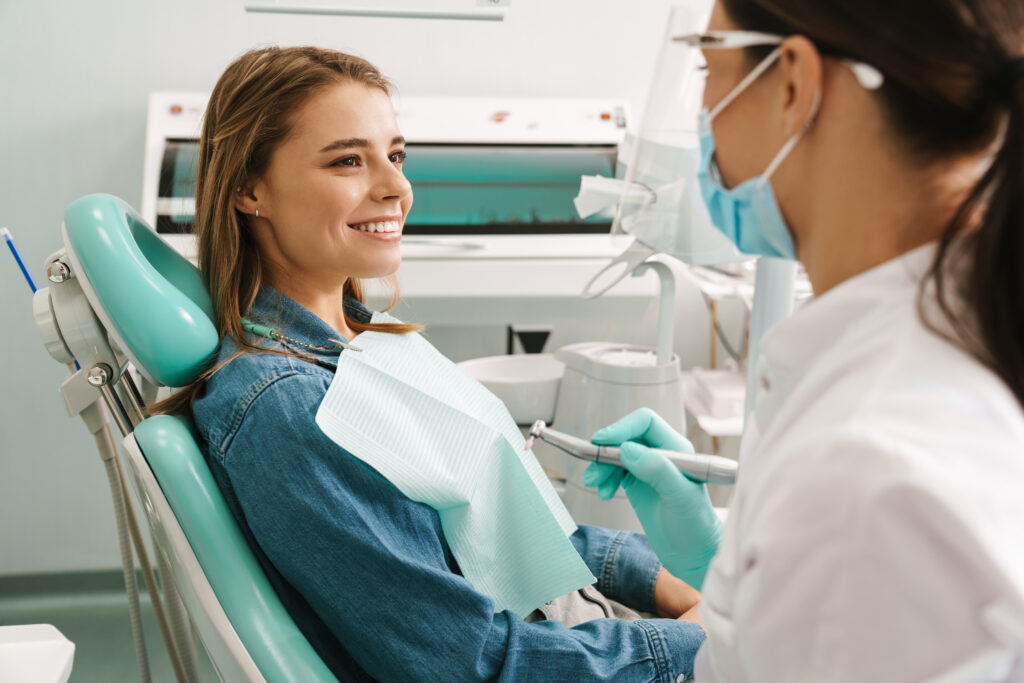 young woman smiling while sitting in medical chair at dental practice