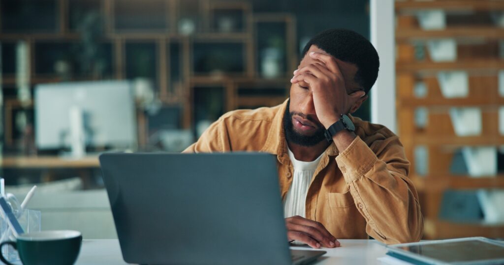 fatigued man sitting at his desk with a hand over his face