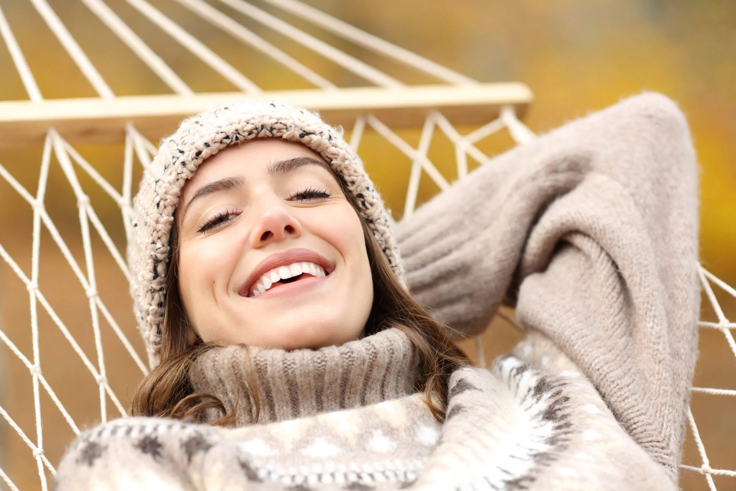 Happy woman lying on a hammock in autumn, perfect smile
